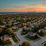 Aerial view of American residential neighbourhood at golden hour with city skyline — new short-term rental laws 2026
