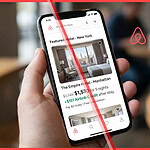 A person holding a smartphone showing an Airbnb hotel listing with a discounted price and a green credit badge, reflecting the new Airbnb lowest price guarantee and loyalty test.
