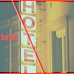 Airbnb logo overlaid on a lit hotel sign at night, representing Airbnb's hotel supply expansion strategy