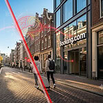 City street with people walking past Booking.com storefront and digital overlay.